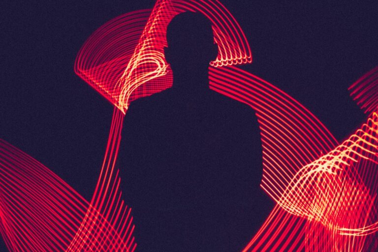 A silhouette of a person surrounded by artistic red light trails, creating a dynamic visual effect.
